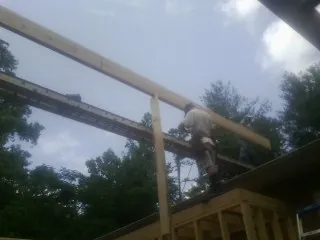 Carpenter setting a ridge beam over a new addition frame — Ice Dam Removal by Roofing Brothers in Angleton